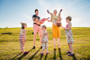 A fun, natural family photo session with little kids and parents at sunset in a park in Winnipeg showing energy, colour, genuine emotion and lots of candid moments.