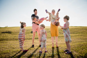 A candid family photo session in a Winnipeg park at sunset with parents and young children capturing natural moments, warm light, colour, and genuine emotion.