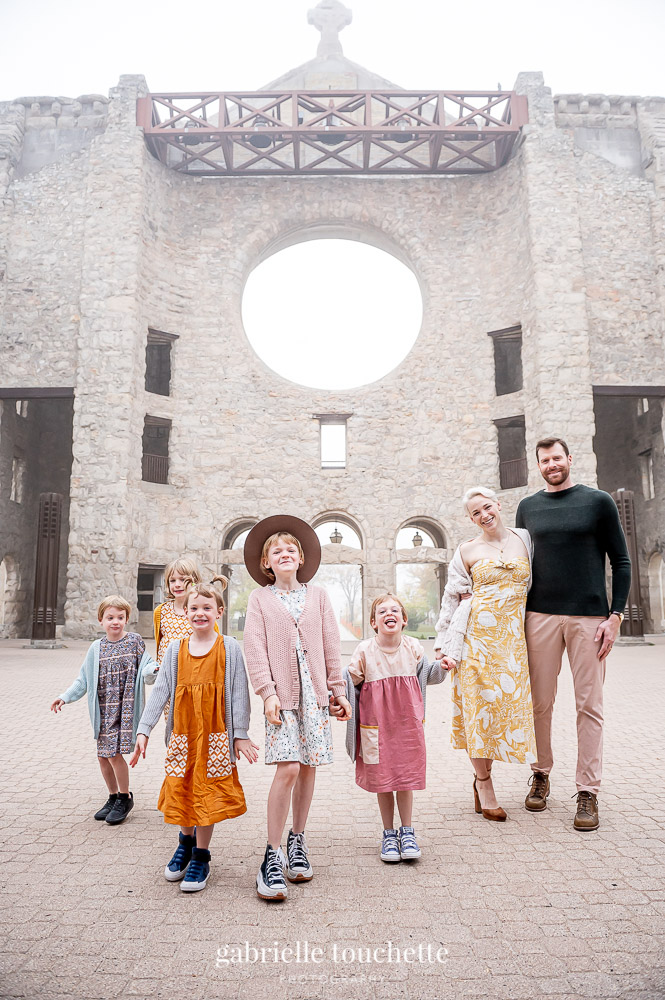 A family photo with kids holding hands at the Saint Boniface cathedral on a foggy morning in Winnipeg