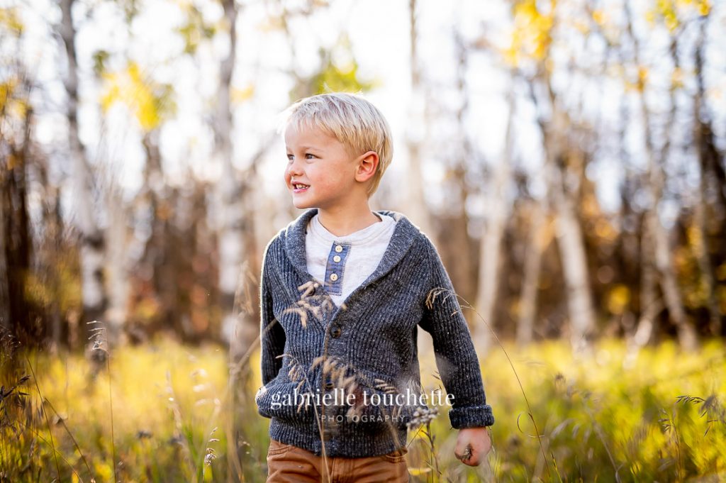 A kid standing in a field for a family photo session at Bois-Des-Esprits