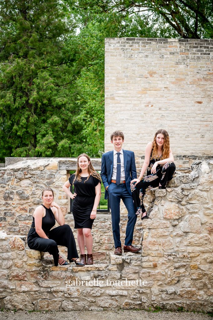 Young adult siblings posing for a group shot on the walls at the Trappist monastery ruins in Saint Norbert Manitoba