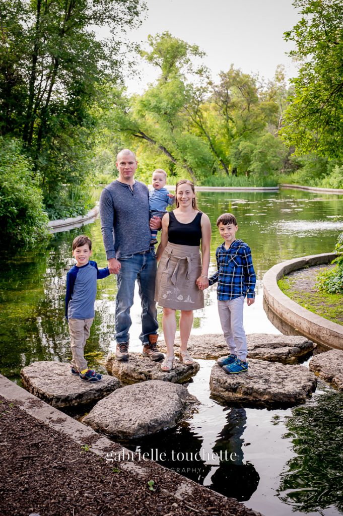 A beautiful family photo location at Assiniboine Park standing on the rocks in the duck Pond