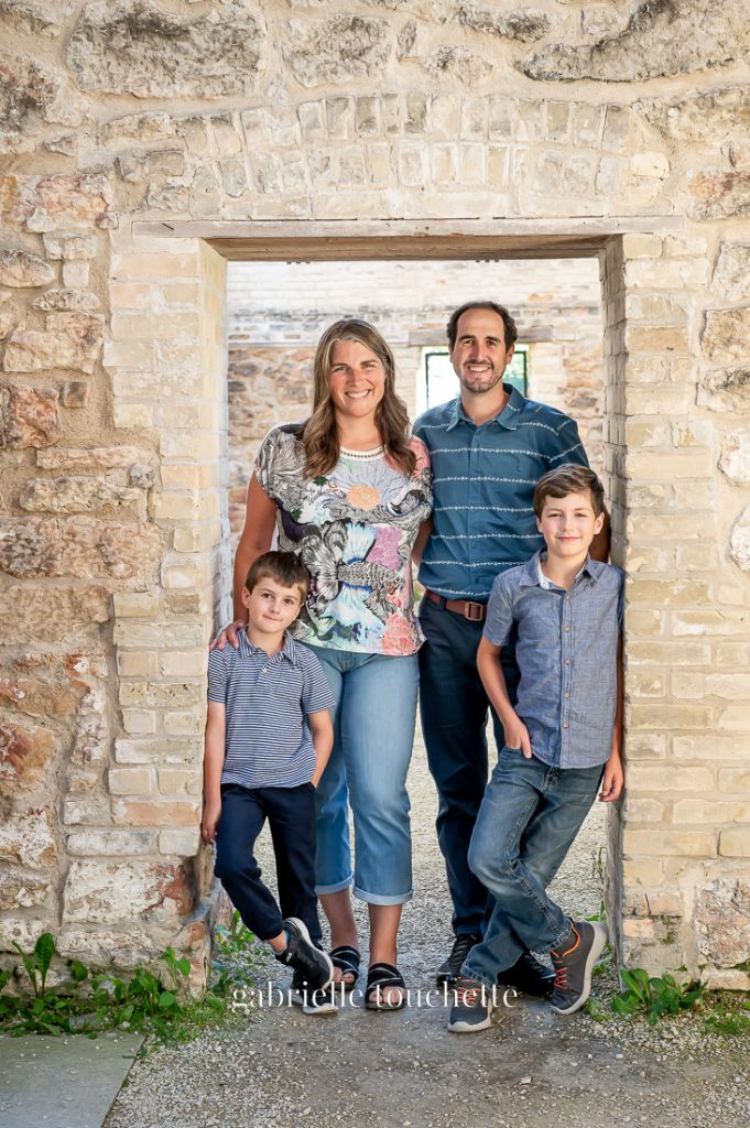 A family posing for a photo in the doorway of a brick façade at the Trappist monastery ruins in Saint Norbert Manitoba