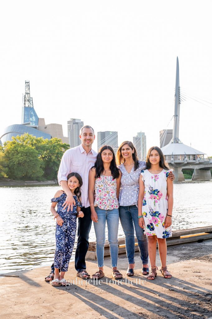 A family photos standing in front of the iconic human rights building and Esplanade Riel in Saint Boniface