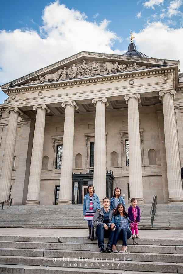 An urban location for Winnipeg family photos at the Manitoba legislative building with concrete steps and historic building with regal columns