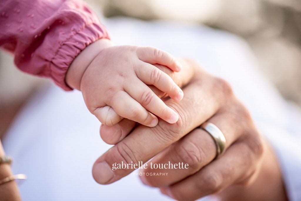 Close-up photo of baby hand on father's hand with the sun shining in the evening