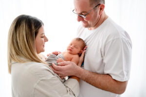 Professional newborn lifestyle photography in Steinbach featuring a natural in-home session with parents and their newborn baby, capturing authentic connection and early family moments.