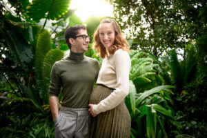 Professional maternity photo session in Winnipeg at The Leaf indoor gardens showing a couple in a relaxed lifestyle setting with natural greenery, creating timeless pregnancy portraits before newborn photos.