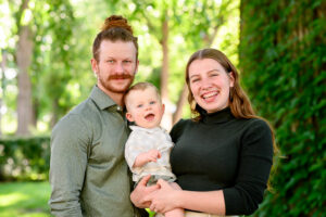 Young parents smiling at the camera with their 1 year old son