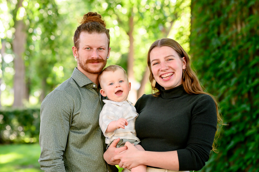 Young parents smiling at the camera with their 1 year old son