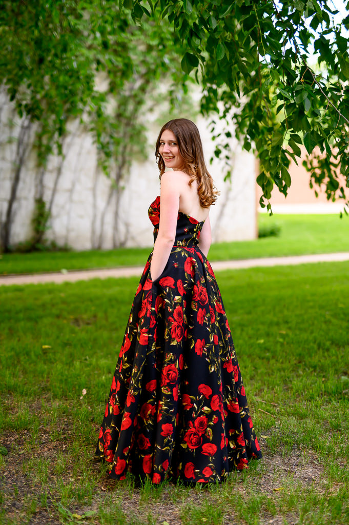 Photo of a grad dress with pockets, posing with a view of the back with grad looking back towards the camera