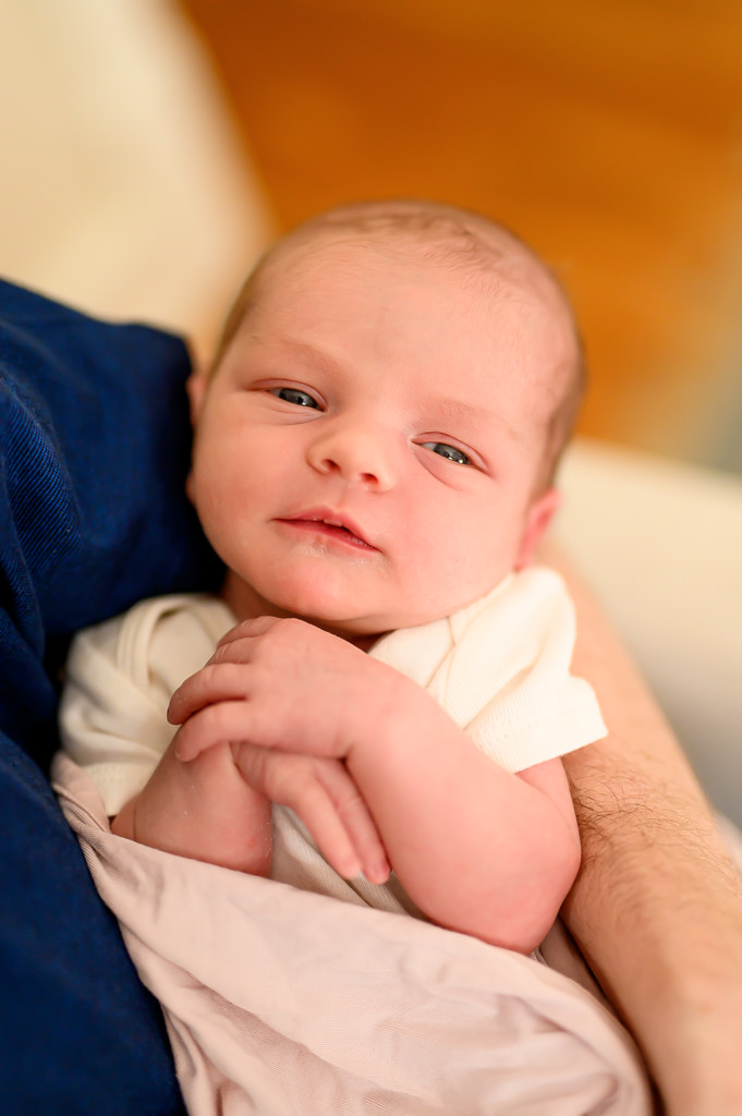a 10-year-old newborn baby at her photo session holding her hands cutely together and smiling in the photo