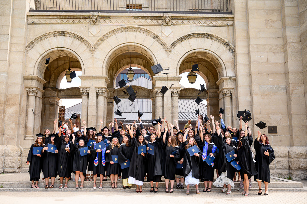 A photo of a university graduation ceremony in Winnipeg after the graduates have tossed their caps in the air.