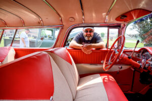 Classic automobile owner posing beside his restored vehicle
