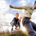 Playful brothers jumping between rocks during a candid family photo session.